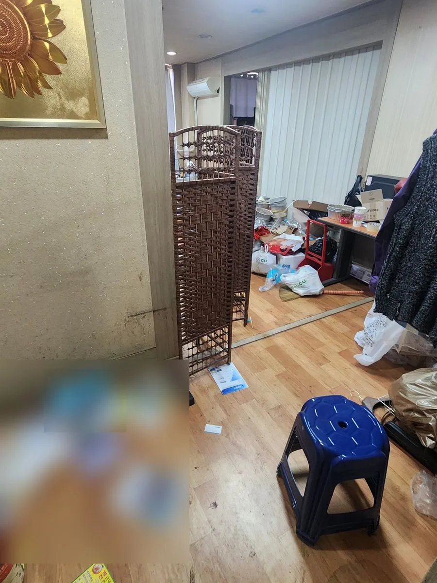 안산 쓰레기집 청소 작업 전 사무 공간 입구 바닥에 전단지와 비닐이 흩어진 모습