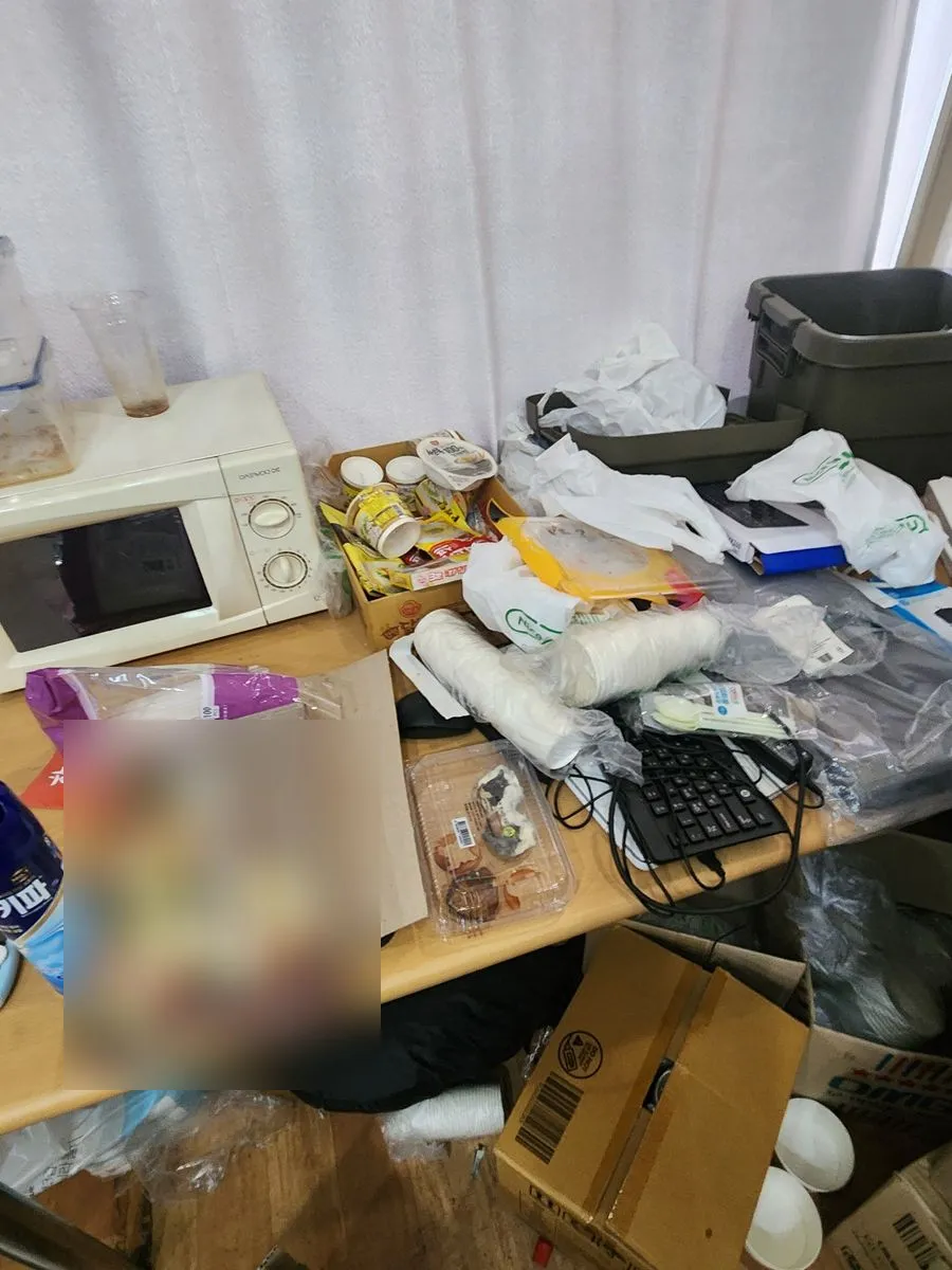 안산 쓰레기집 청소 작업 전 탁자 위에 음식 용기와 비닐, 상자가 쌓인 모습
