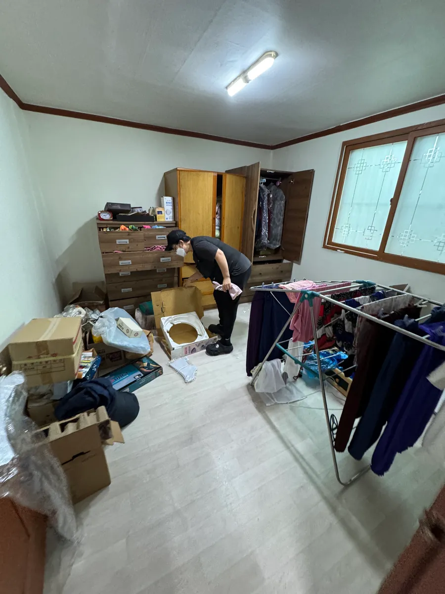 안산 유품정리 작업 전, 박스와 옷가지가 쌓인 방 안