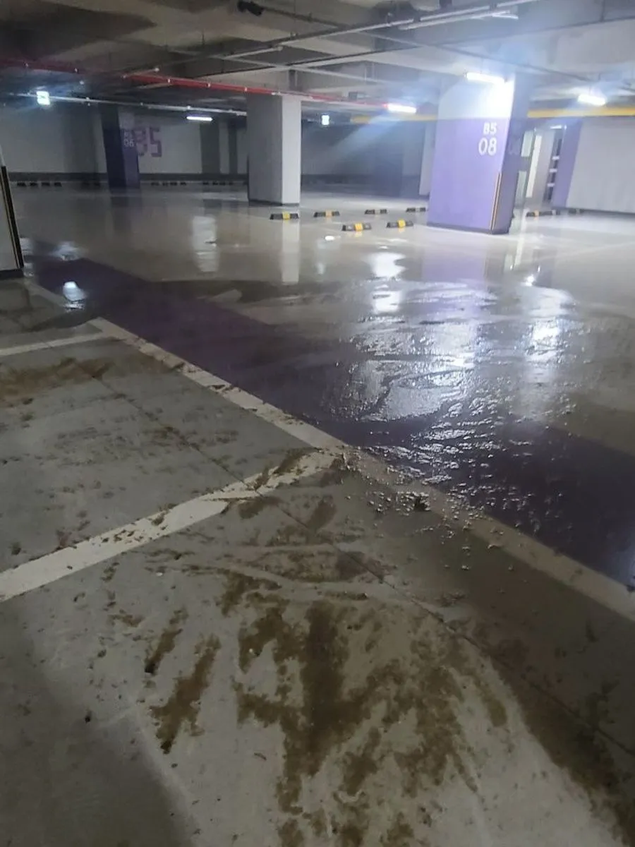 안양 침수청소 작업 전 넓게 진흙 자국이 이어진 주차장 바닥