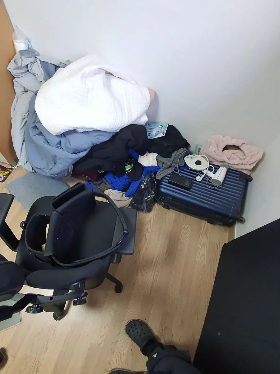 안양 쓰레기집 청소 작업 전 의자 뒤로 옷가지와 가방이 쌓인 모습