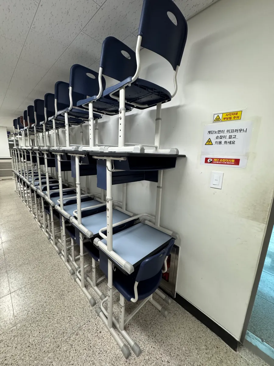 강남 학교 바닥왁스코팅 전 책상 위에 의자를 올려 한쪽 벽으로 옮겨 둔 모습