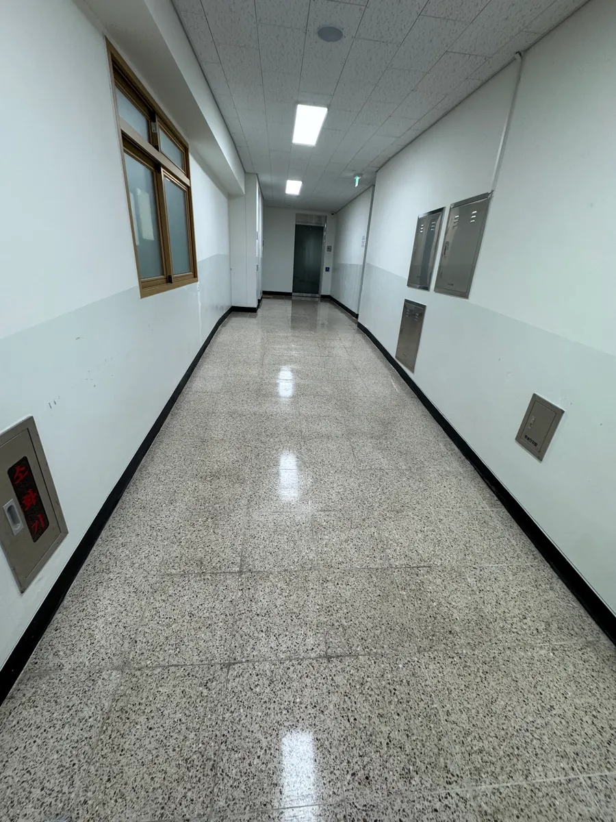 강남 바닥왁스코팅 작업 완료 후 천장 조명이 비치는 학교 복도 바닥