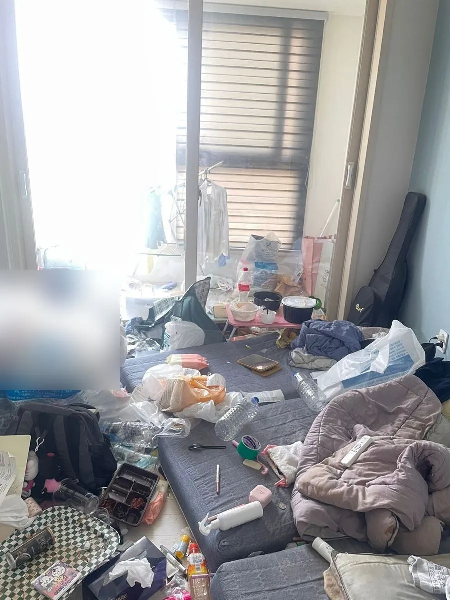 군포 쓰레기집 청소 작업 전 창가 쪽 바닥에 빈 병과 봉지가 쌓인 모습