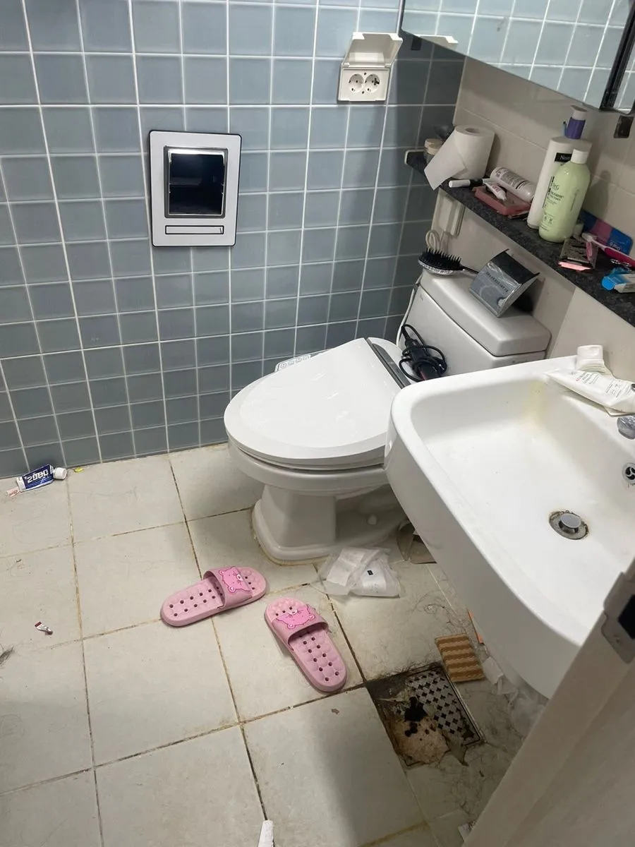 군포 쓰레기집 청소 작업 전 욕실 바닥에 쓰레기가 흩어지고 배수구에 이물질이 쌓인 모습
